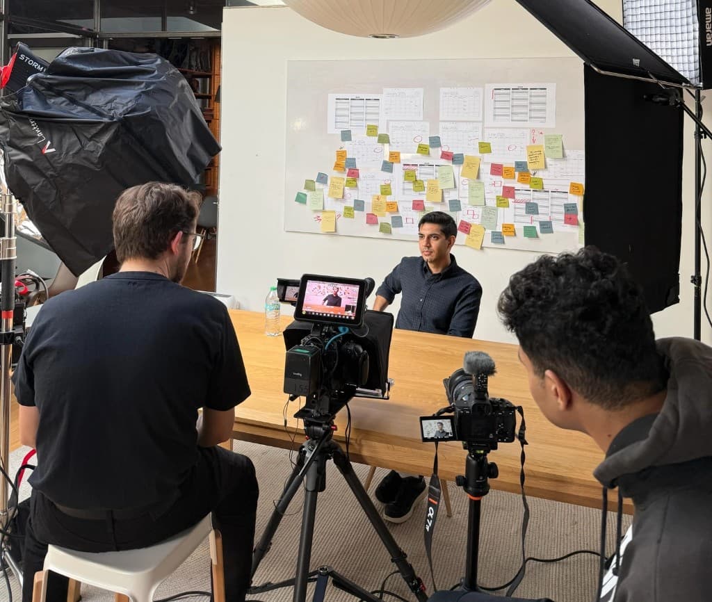 A creative team filming a video shoot on set with lighting and multiple cameras